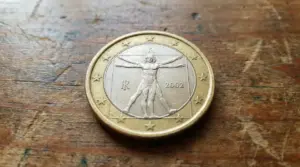 Moneta da 1 euro del 2002 con l'Uomo Vitruviano su sfondo in legno