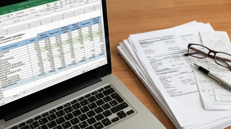 Computer portatile con foglio Excel aperto e documenti contabili su un tavolo
