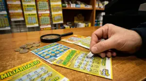 Persona gratta un biglietto Gratta e Vinci su un bancone di una tabaccheria