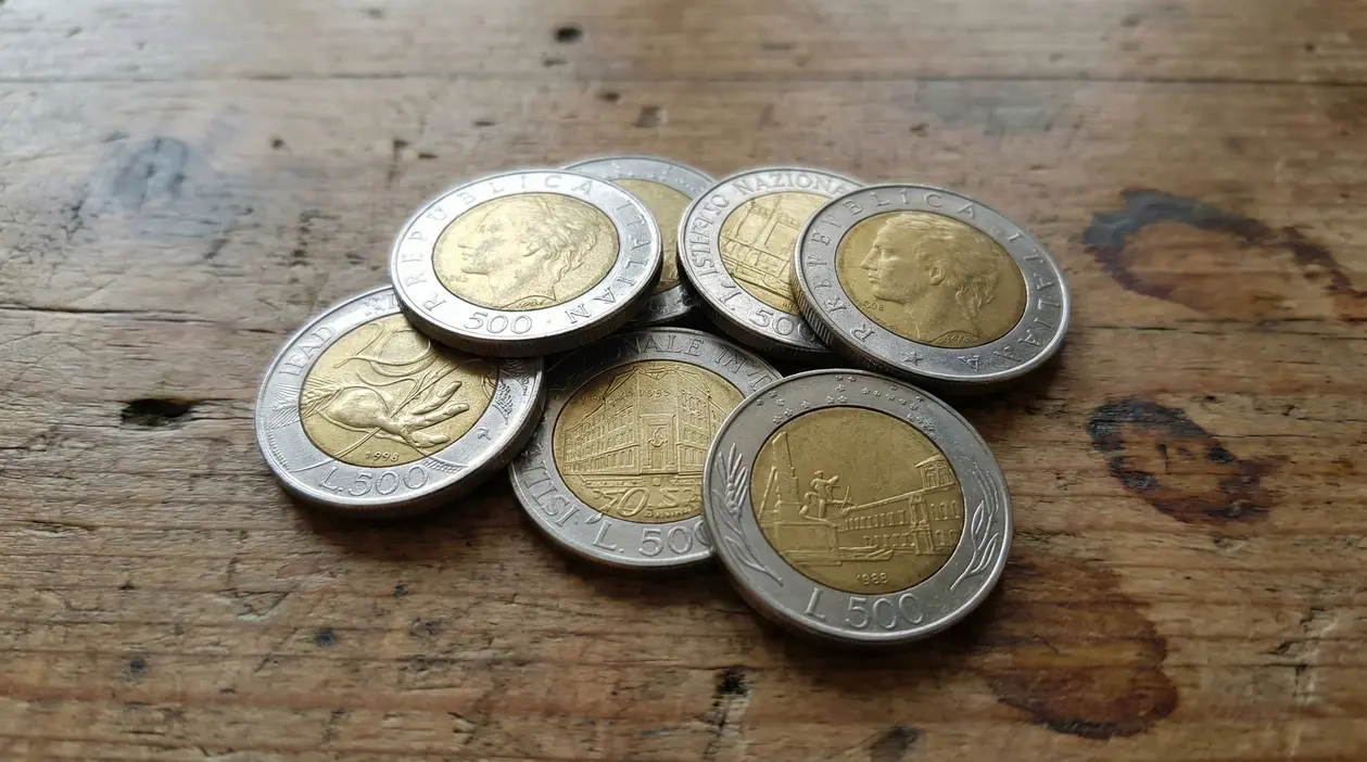 Monete italiane da 500 lire bimetalliche su un tavolo in legno